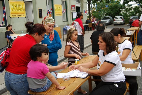 BesucherInnen des Straßenfestes reden mit einer Mitarbeiterin der Gebietsbetreuung und füllen einen Fragebogen aus. © kon-text
